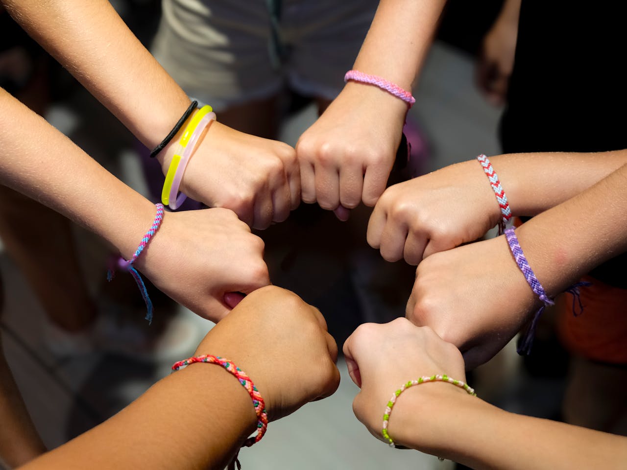 home-hero A diverse group of hands wearing colorful friendship bracelets in unity.